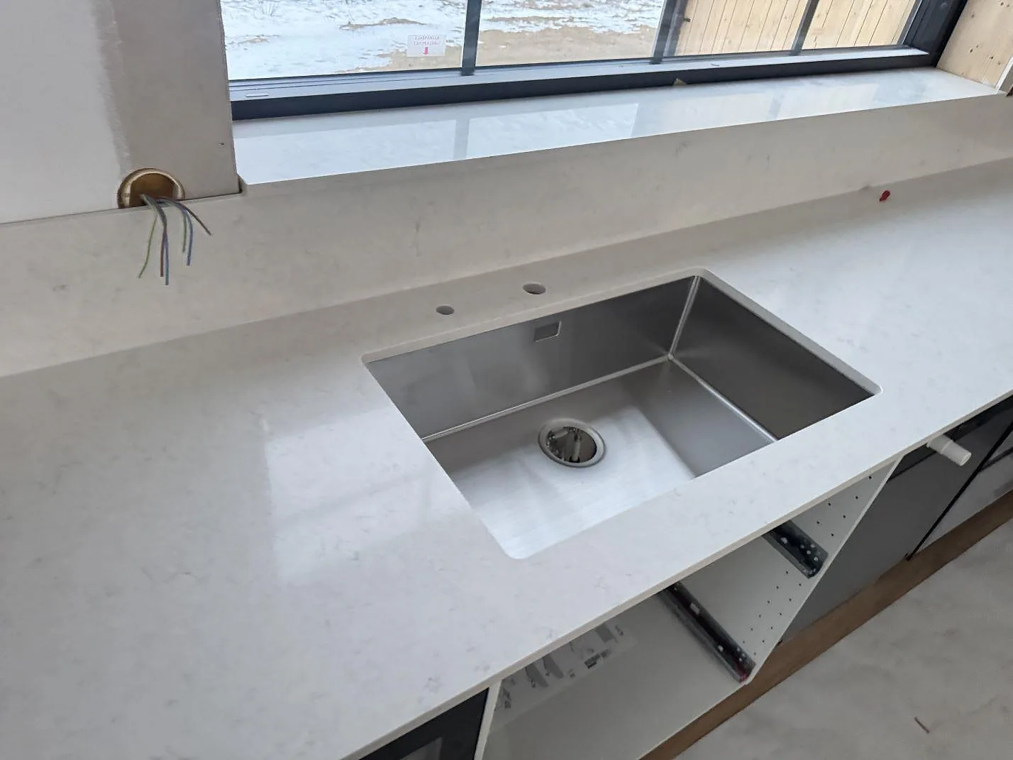 Närbild på polerad Silestone Snowy Ibiza bänkskiva med rostfri diskho, stänkkant och fönsterbänk i Alvesta.