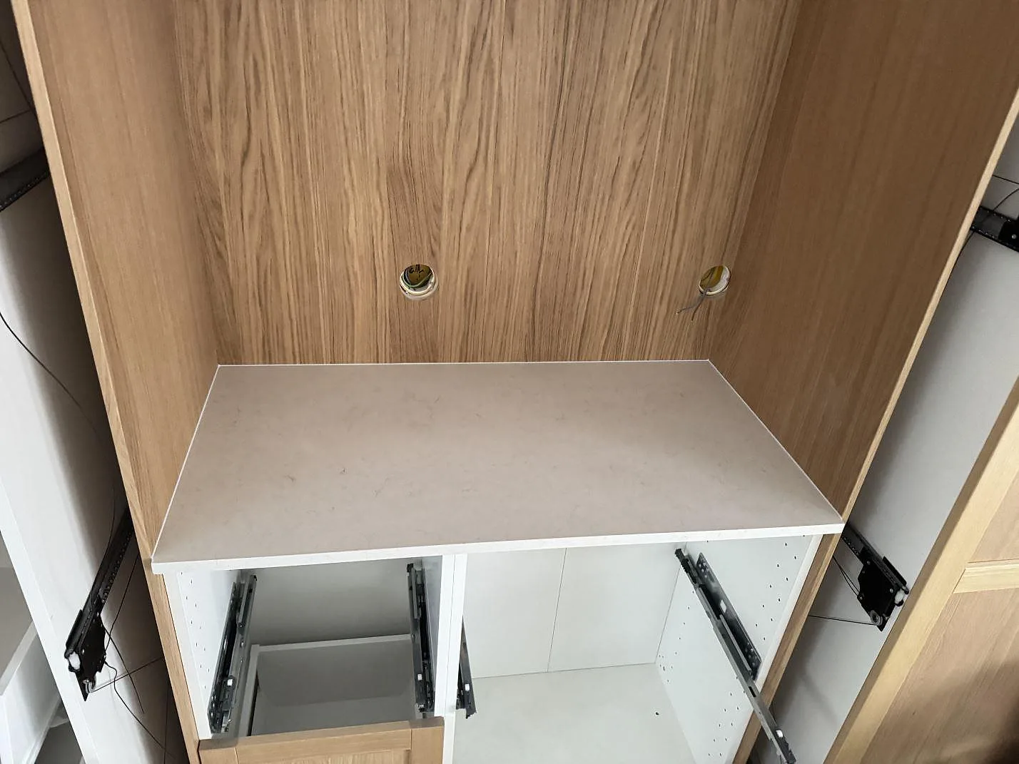 Separat nisch med kort bänkyta i polerad Silestone Snowy Ibiza och träinredning under köksmontering i Alvesta.