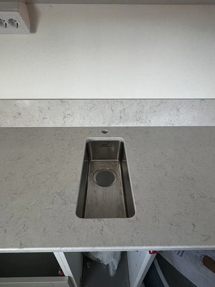 Underlimmad metallfärgad diskho i polerad Silestone Snowy Ibiza med synlig ådring och stänkkant i Båstad.