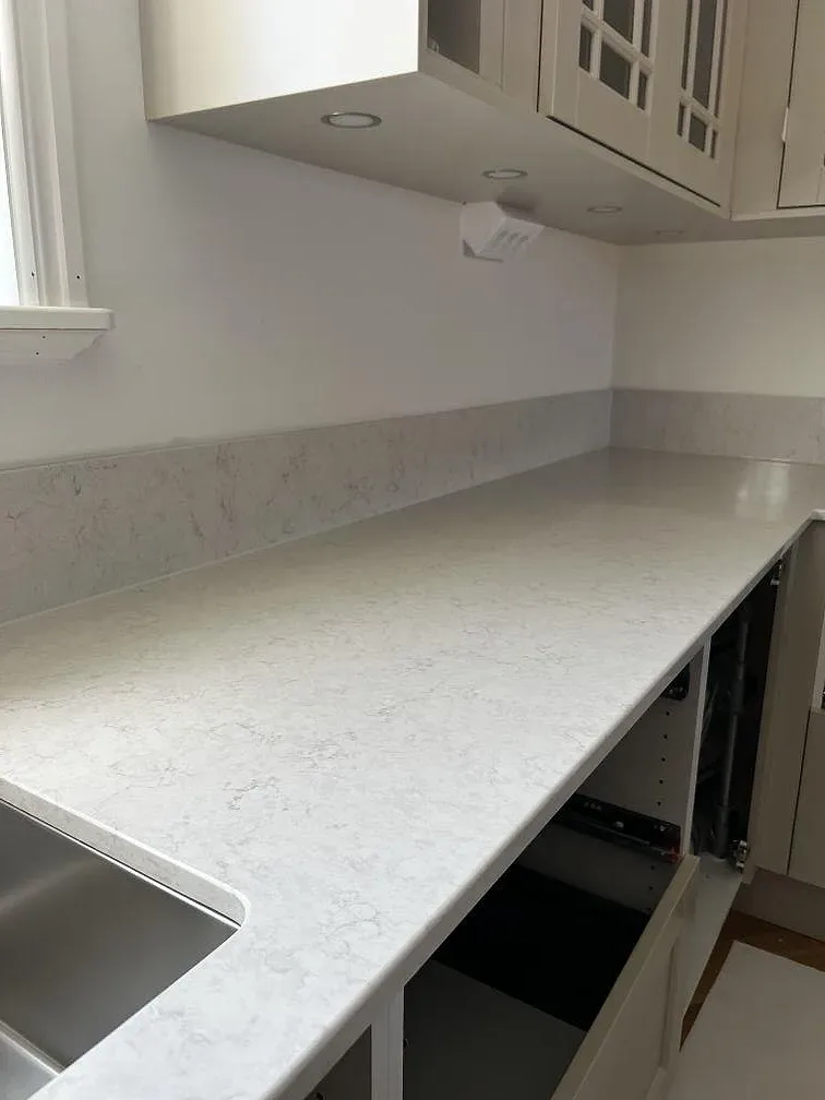 Sidovy av polerad köksbänkskiva i Silestone Snowy Ibiza med uppvikt stänkkant och diskhoöppning i Båstad.
