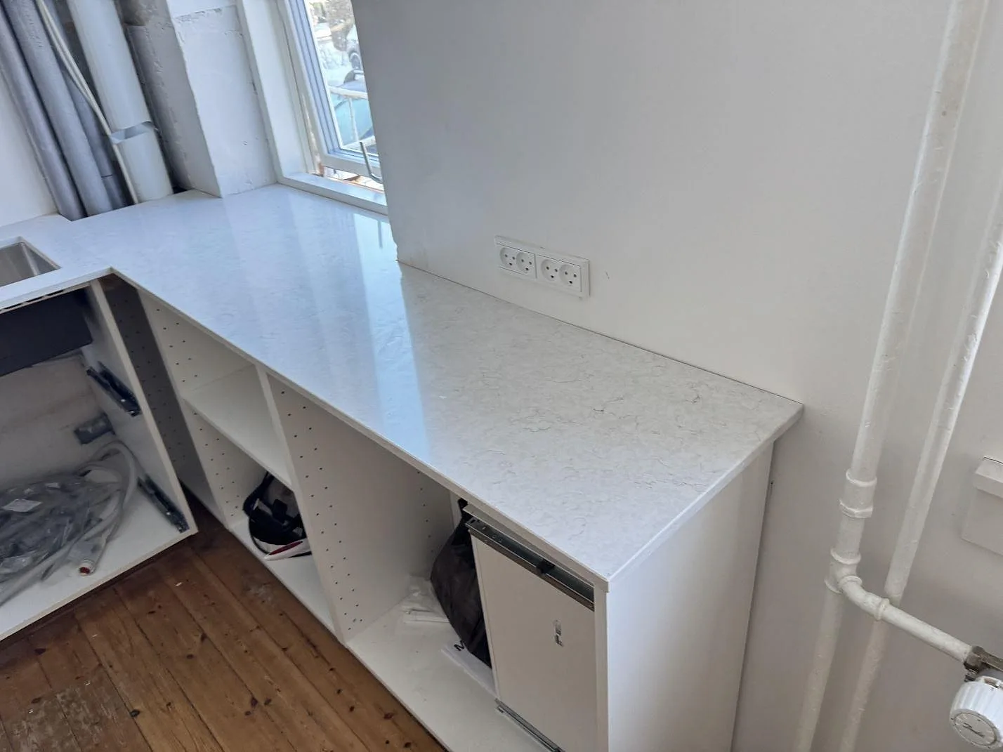Rak köksbänkskiva i polerad Silestone Snowy Ibiza längs öppna stommar och vägguttag i ett kök i Bagsværd.