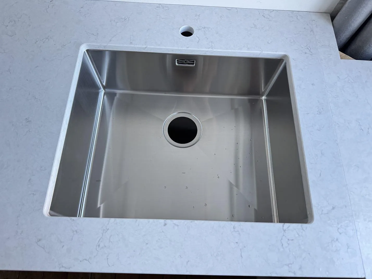 Närbild på underlimmad rostfri diskho i polerad Silestone Snowy Ibiza köksbänkskiva i ett kök i Bagsværd.