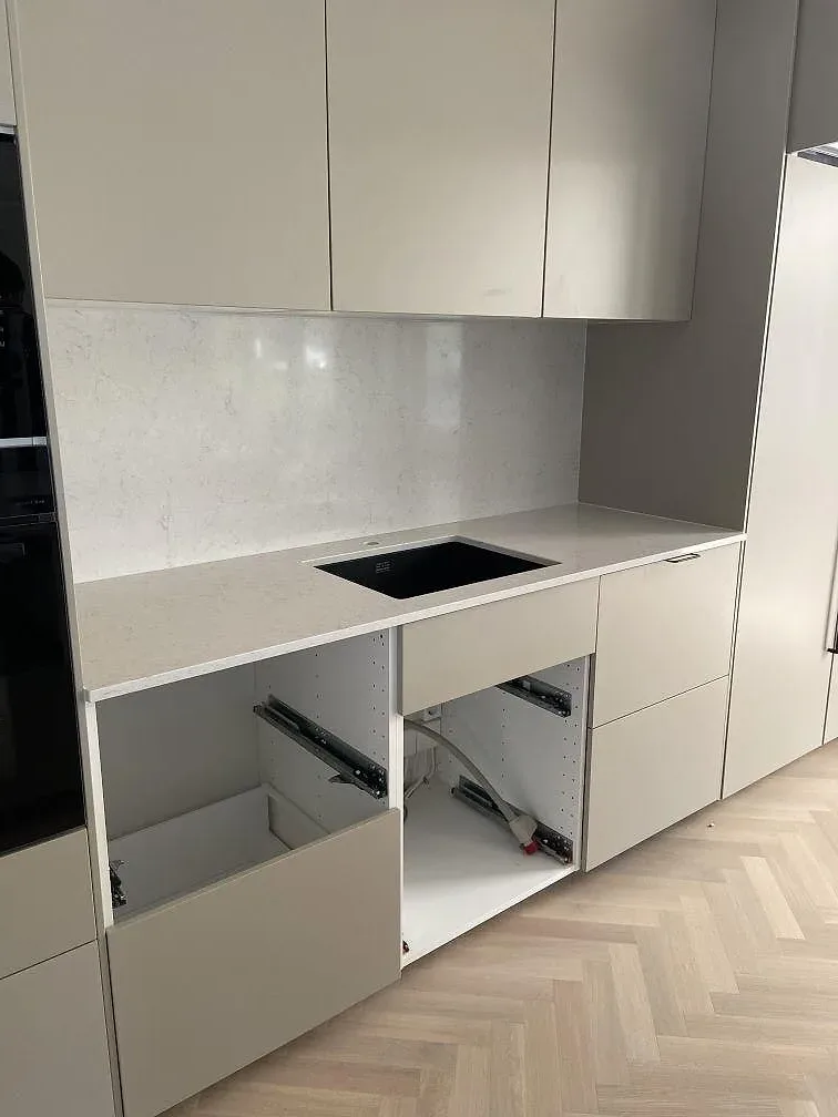 Vit Silestone Snowy Ibiza bänkskiva med hällurtag och öppna underskåp under installation i ett kök i Bara.