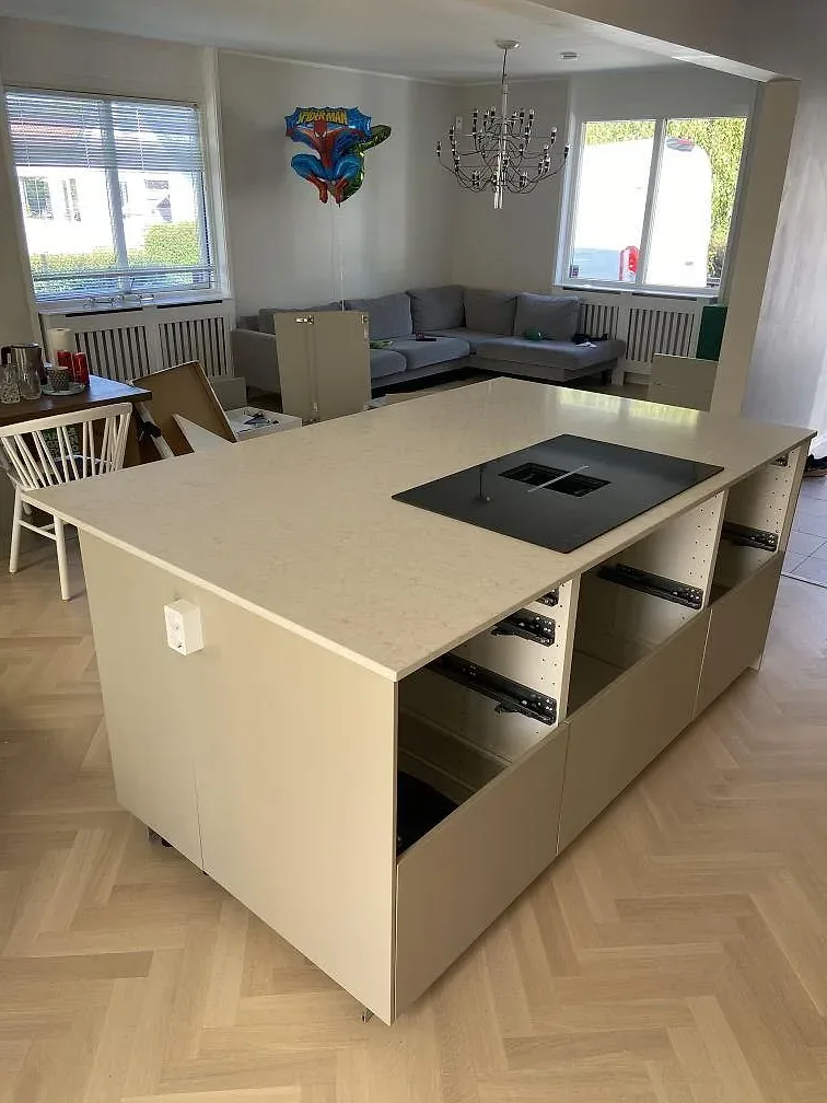 Fristående köksö i polerad Silestone Snowy Ibiza i öppet kök mot vardagsrum, fotad under montering i Bara.