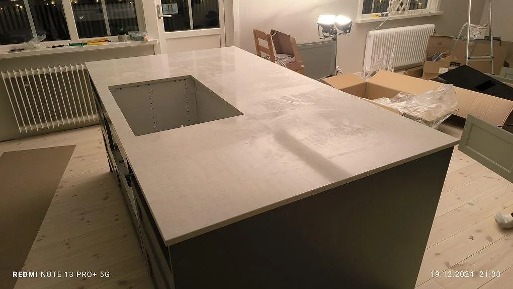 Köksö i polerad Silestone Snowy Ibiza med hällöppning och ljus komposityta i Bjursås, fotograferad under montering.