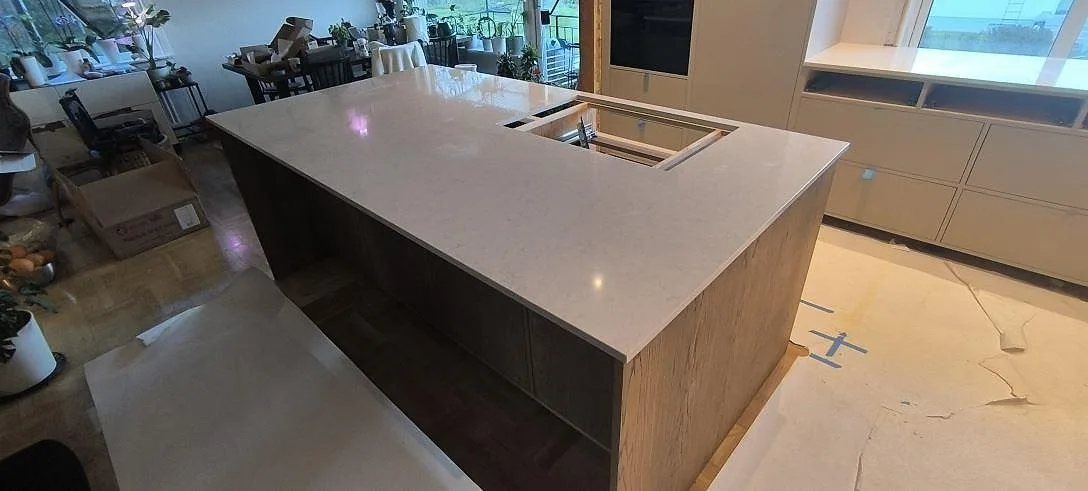 Närbild på polerad Silestone Snowy Ibiza som köksö i Bjursås, med öppning för häll och ljus kvartskomposityta.