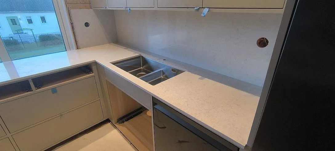 Diskzon i Bjursås med polerad köksbänkskiva och stänkskydd i Silestone Snowy Ibiza, ljus kvartskomposit runt synlig ho.