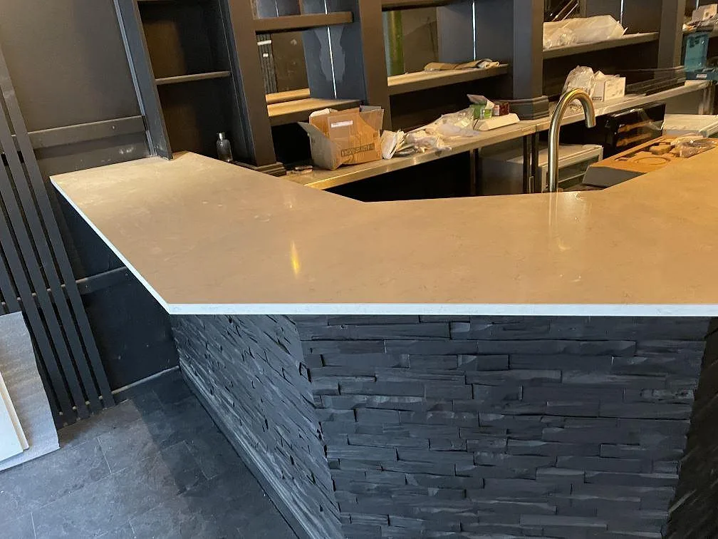 Vinklad bardisk i vit Silestone Snowy Ibiza komposit på mörk stenfront i en bar i Borås.