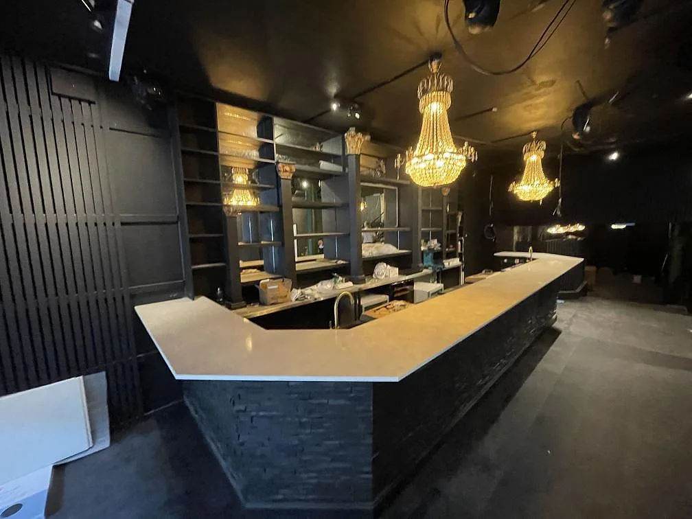 Bardisk i vit polerad Silestone Snowy Ibiza komposit med mörk skifferklädd front i en restauranglokal i Borås.