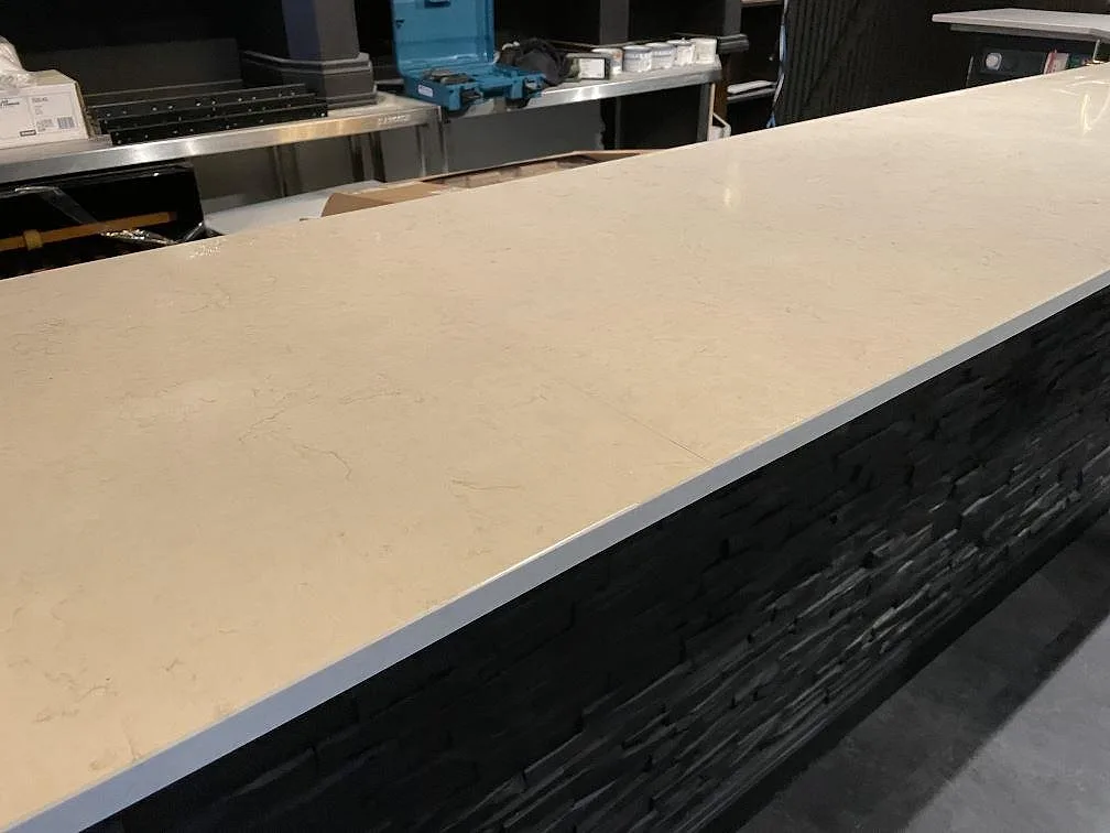 Detalj av vit polerad Silestone Snowy Ibiza komposit på mörk skifferklädd bardisk i Borås.