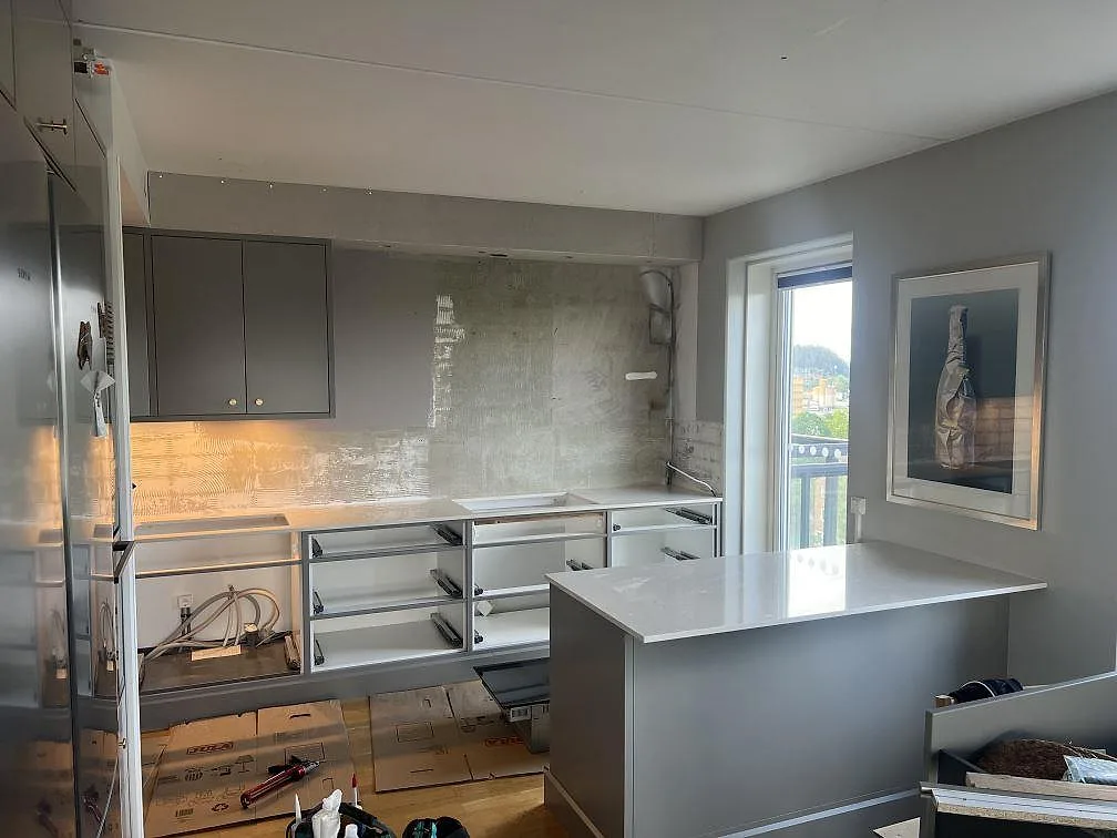 Köksbänkskiva och köksö i polerad Silestone Snowy Ibiza, 20 mm kvartskomposit, i ett grått kök under montering i Borås.