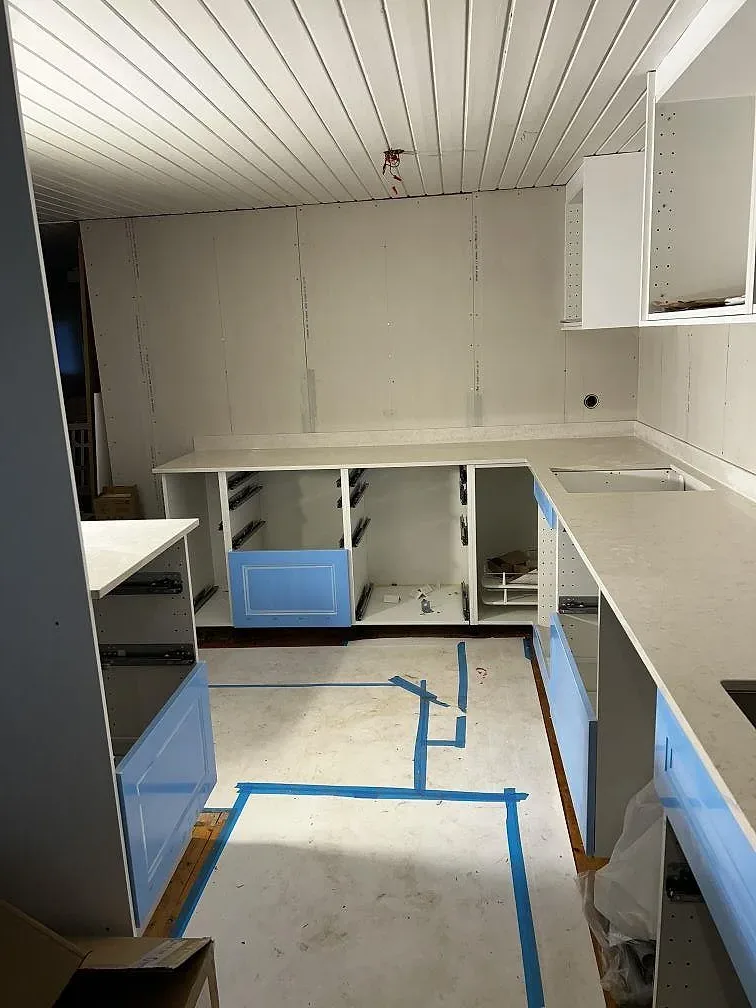 Polerad Silestone Snowy Ibiza som köksbänkskiva och köksö i ett kök under renovering i Borrby.