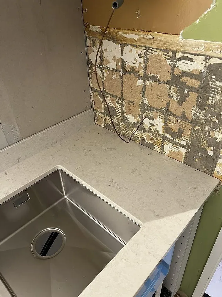 Närbild på polerad Silestone Snowy Ibiza med ljus ådring och underlimmad rostfri diskho i ett kök i Borrby.