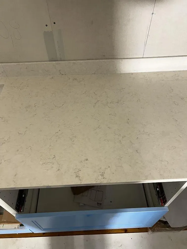 Yta av polerad Silestone Snowy Ibiza på köksbänk intill blå köksluckor under montering i Borrby.