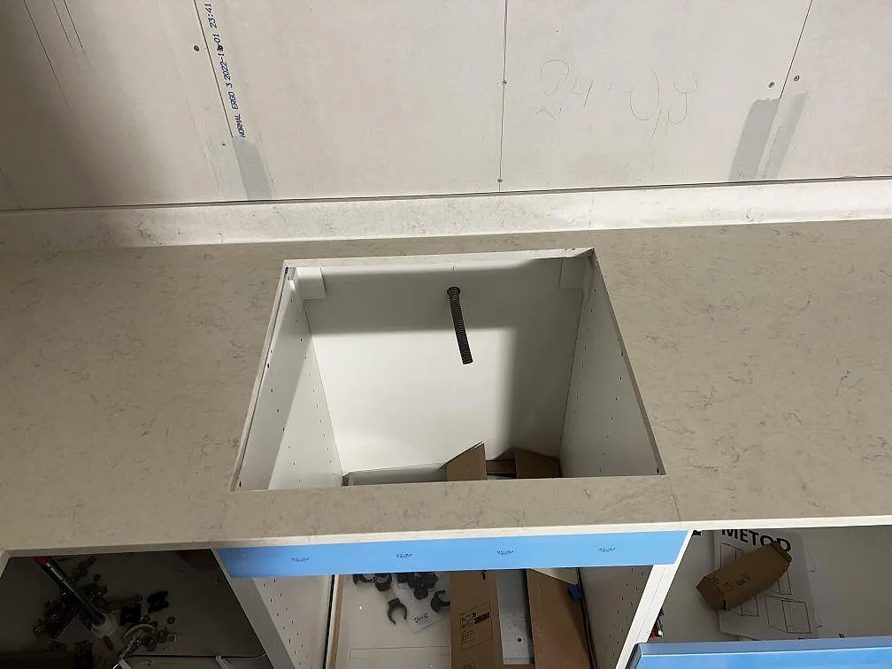 Köksbänkskiva i polerad Silestone Snowy Ibiza med urtag för häll och blå skyddstejp under montering i Borrby.