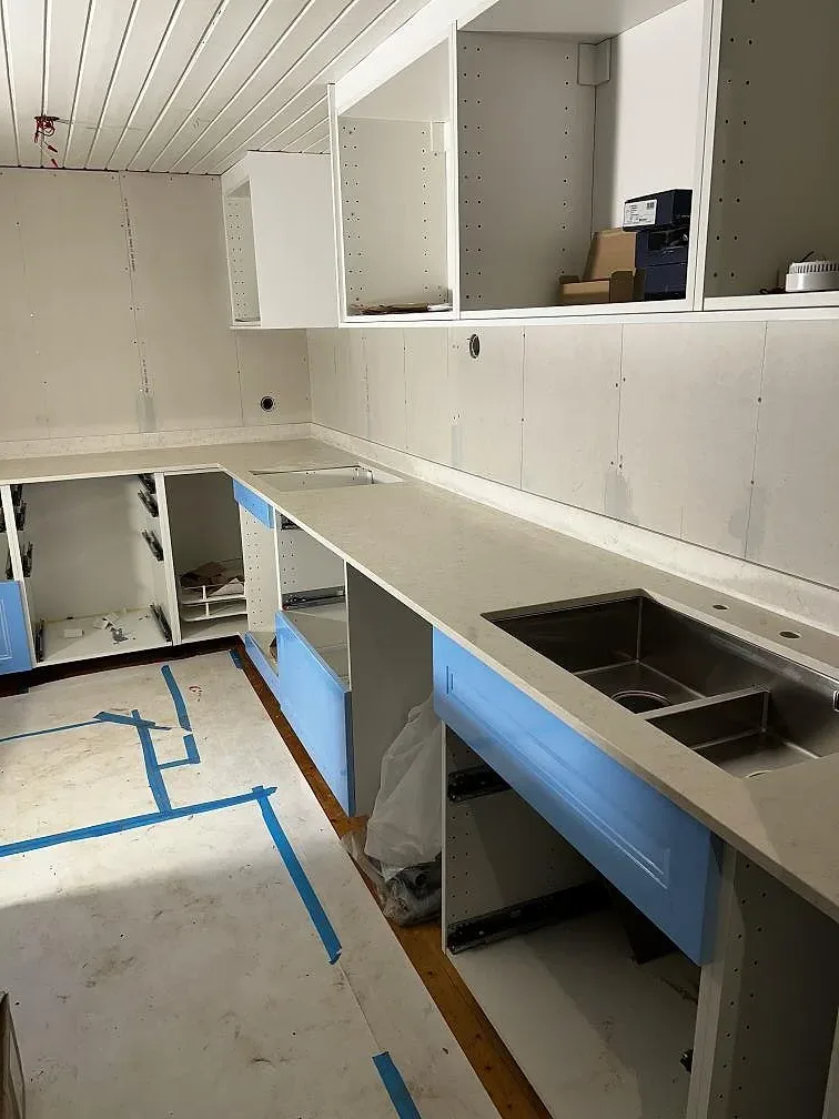 Köksbänkskiva och köksö i polerad Silestone Snowy Ibiza med dubbel underlimmad rostfri diskho under montering i Borrby.