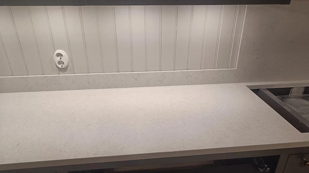 Ytdetalj av polerad Silestone Snowy Ibiza, vit komposit i kök med uppvikt stänkkant och diskret ådring i Braås.