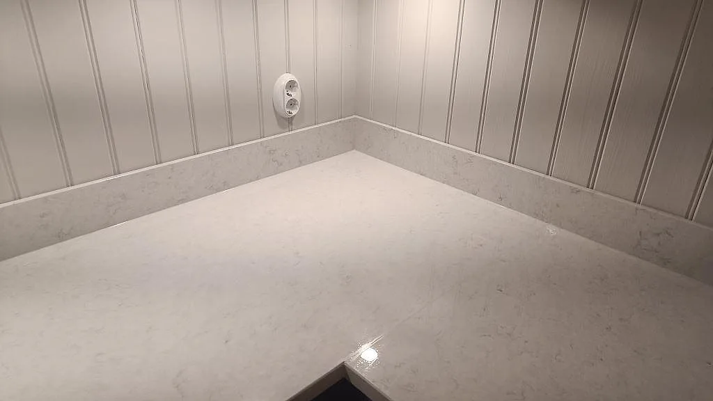 Närbild på hörnet i en polerad Silestone Snowy Ibiza köksbänkskiva med uppvikt stänkkant och pärlspont i Braås.