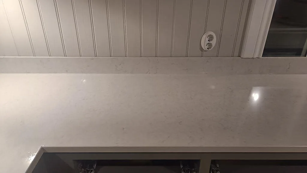 Polerad Silestone Snowy Ibiza bänkskiva framför fönster i Braås, med låg stänkkant och ljus stenådring.