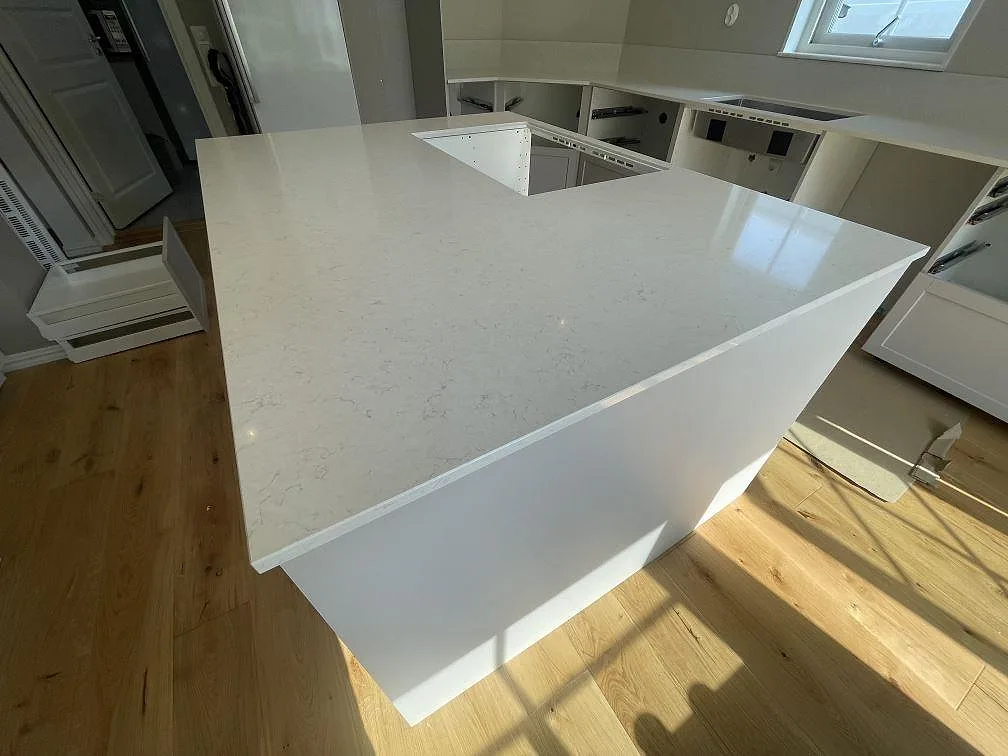Närbild på köksö med polerad vit Silestone Snowy Ibiza komposit och mjuk grå ådring i ett kök i Bro.