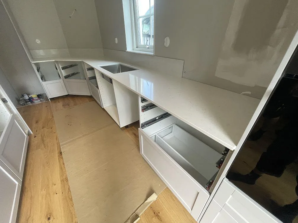 Polerad köksbänkskiva i Silestone Snowy Ibiza komposit med synlig diskho och låg stänkkant vid fönster i Bro.