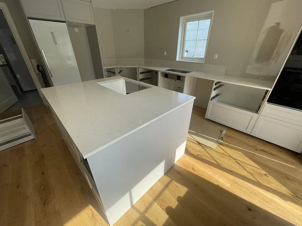 Köksbänkskiva i polerad Silestone Snowy Ibiza komposit med köksö och väggbänk under montering i Bro.