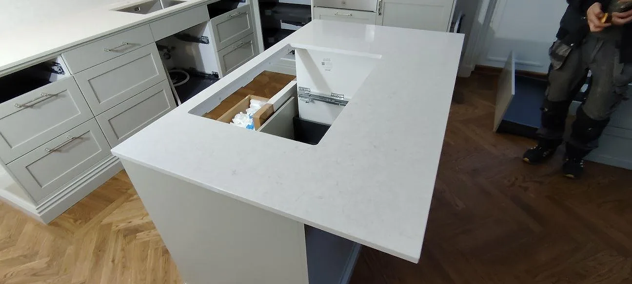 Köksö i polerad Silestone Snowy Ibiza med större rektangulärt urtag i den ljusa kompositytan i Bromma.