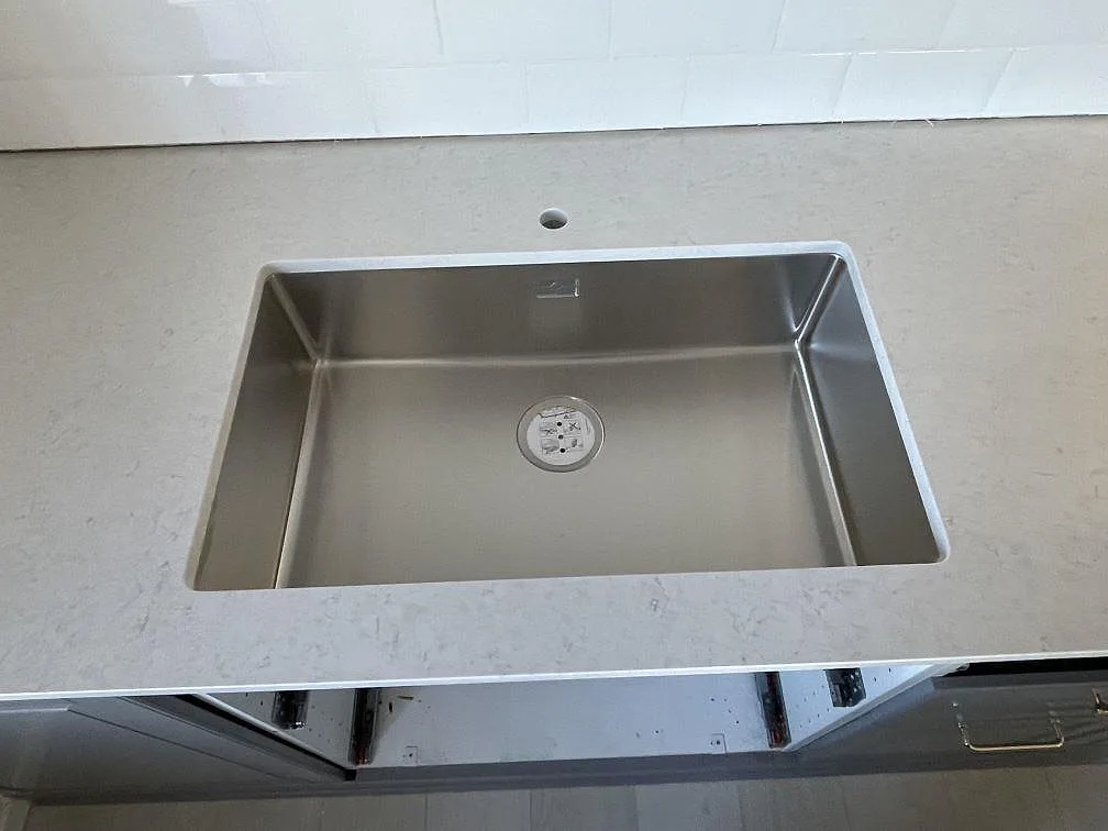 Topvy av den polerade köksbänkskivan i Silestone Snowy Ibiza med en stor underlimmad rostfri diskho i ett kök i Bromma.