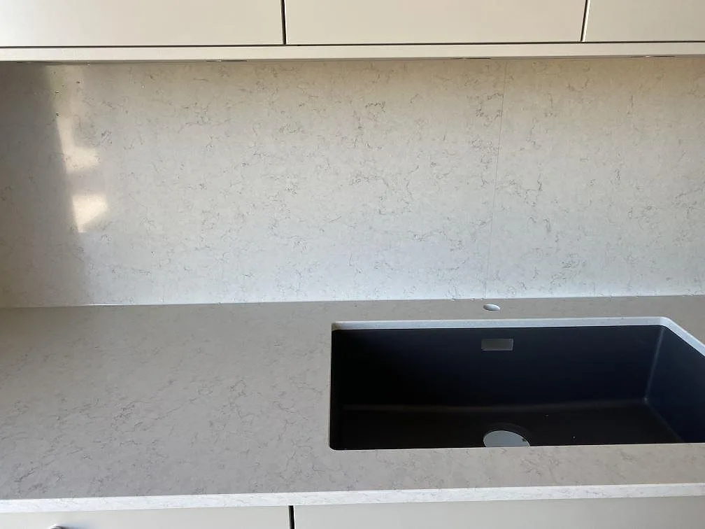 Underlimmad mörk diskho i en polerad Silestone Snowy Ibiza köksbänk med separat borrat blandarhål i stenen, Bunkeflostrand.