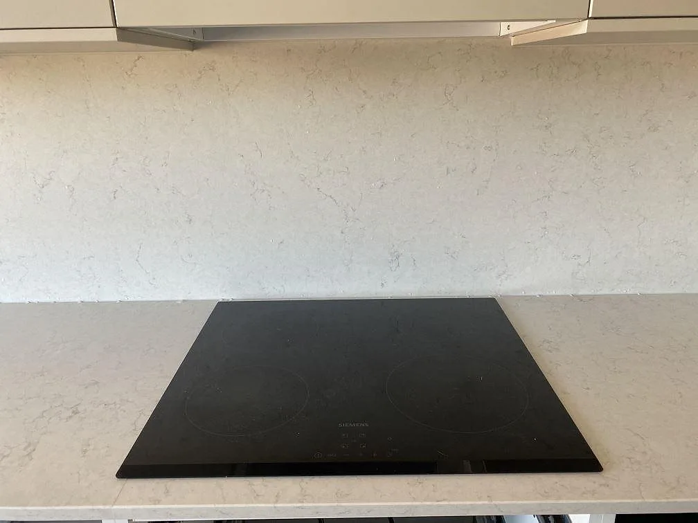 Infälld Siemens induktionshäll i en köksbänk av Silestone Snowy Ibiza med heltäckande stänkvägg i samma ljusa sten, Bunkeflostrand.