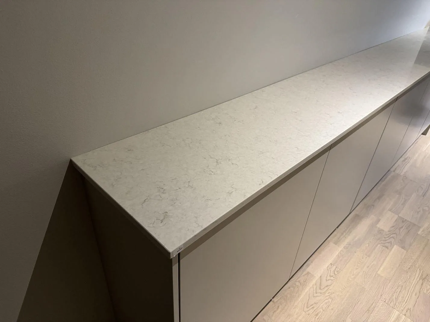 Bänkskiva i vit Silestone Snowy Ibiza, polerad, på en låg skåpsrad mot vägg i Bunkeflostrand.