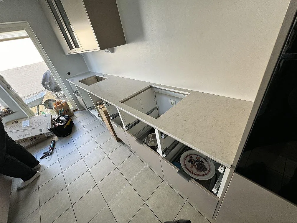 Lång köksbänkskiva i polerad Silestone Snowy Ibiza komposit med underlimmad rostfri diskho och hällurtag under montering i Bunkeflostrand.