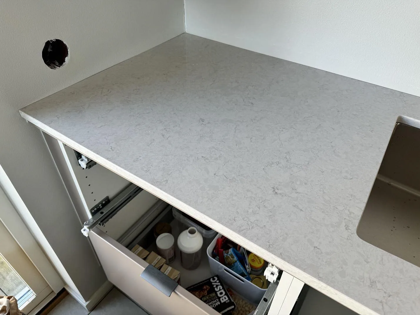 Närbild av polerad Silestone Snowy Ibiza köksbänkskiva med underlimmad diskho och öppen köksstomme i Bunkeflostrand.
