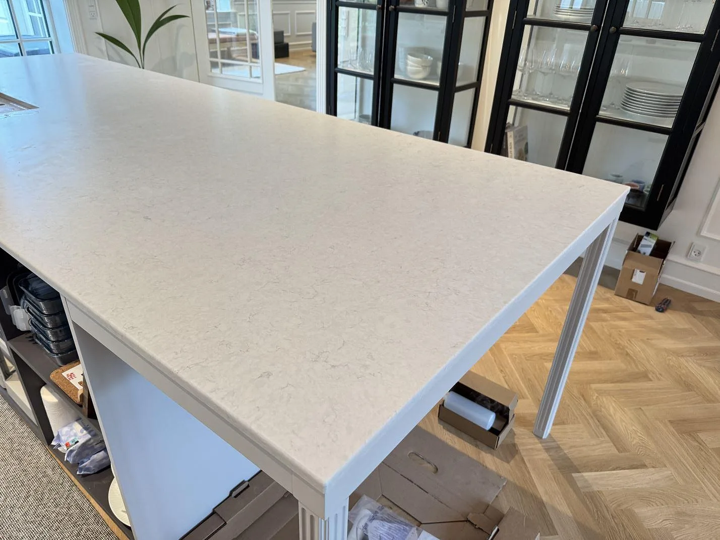 Bred köksö i matt Silestone Snowy Ibiza, ljus kvartskomposit med diskret grå ådring, under montering i Charlottenlund.