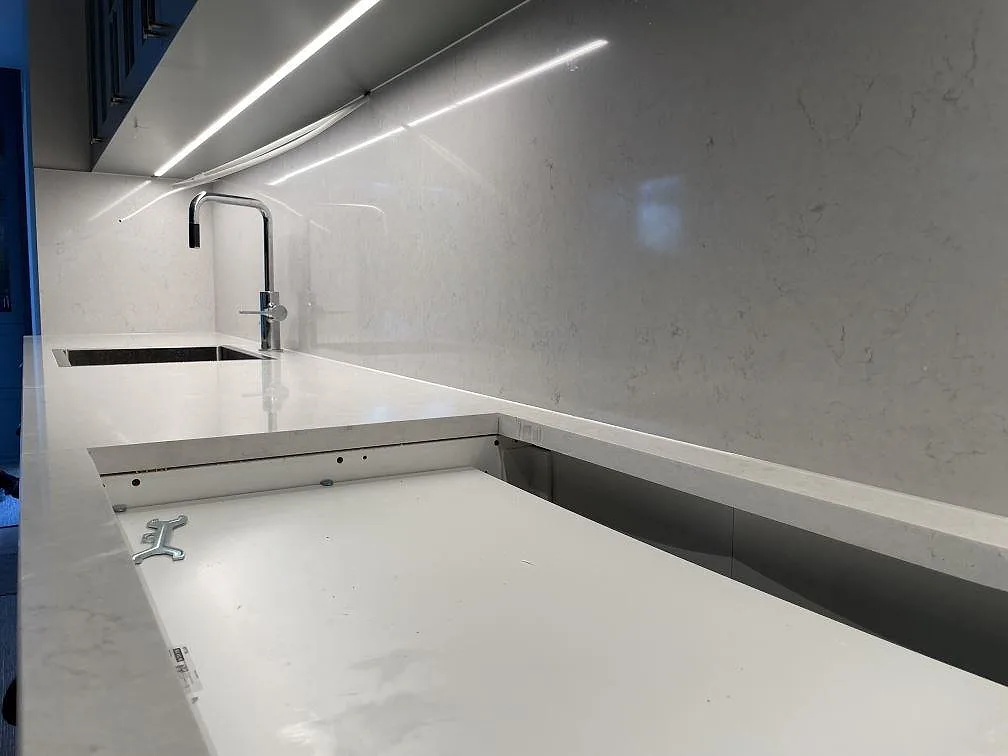 Närbild av Silestone Snowy Ibiza i komposit med polerat stänkskydd, hällöppning och ljus ådring i Danderyd.