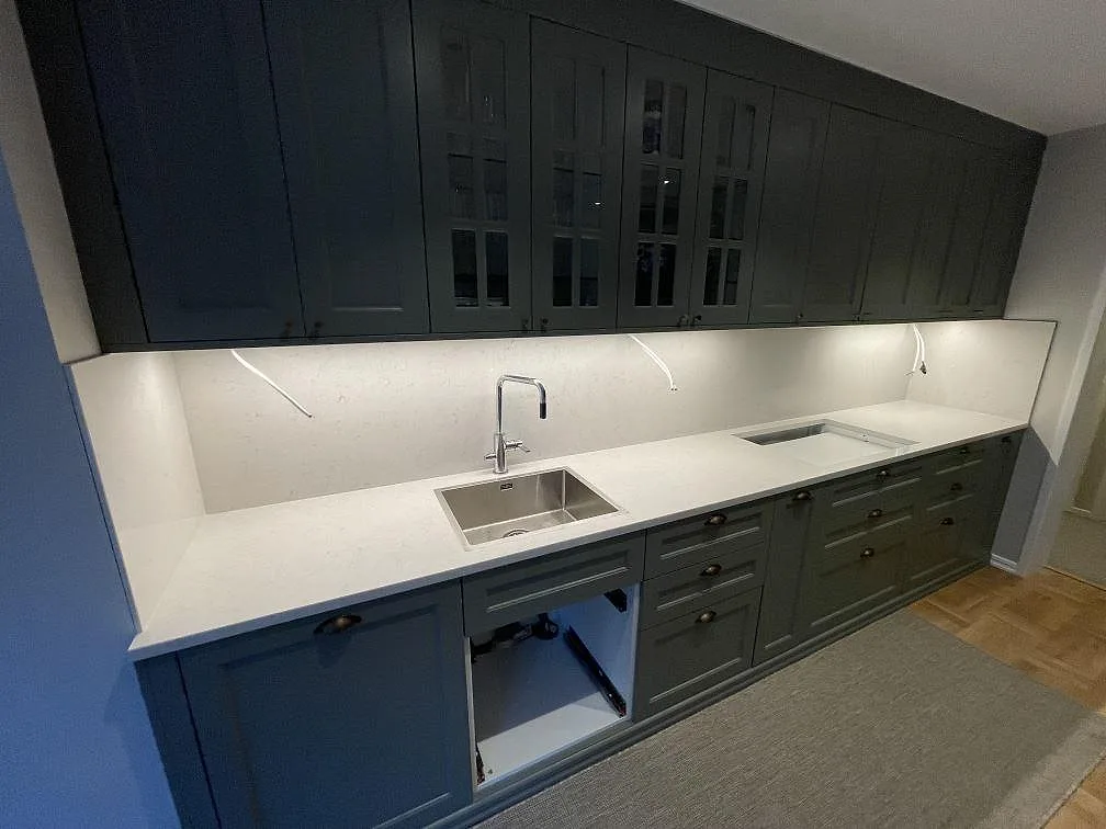 Köksbänkskiva och stänkskydd i Silestone Snowy Ibiza, komposit med Mocka och polerade delar, i ett kök med mörka luckor i Danderyd.