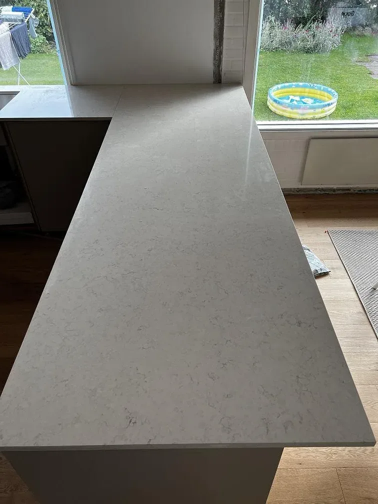 Polerad Silestone Snowy Ibiza som bred köksbänkskiva på halvö med ljus ådring och trädgårdsfönster i Dyssegård.