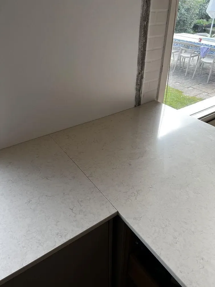 Detalj av skarv och hällurtag i polerad Silestone Snowy Ibiza på köksbänk vid fönster i Dyssegård.