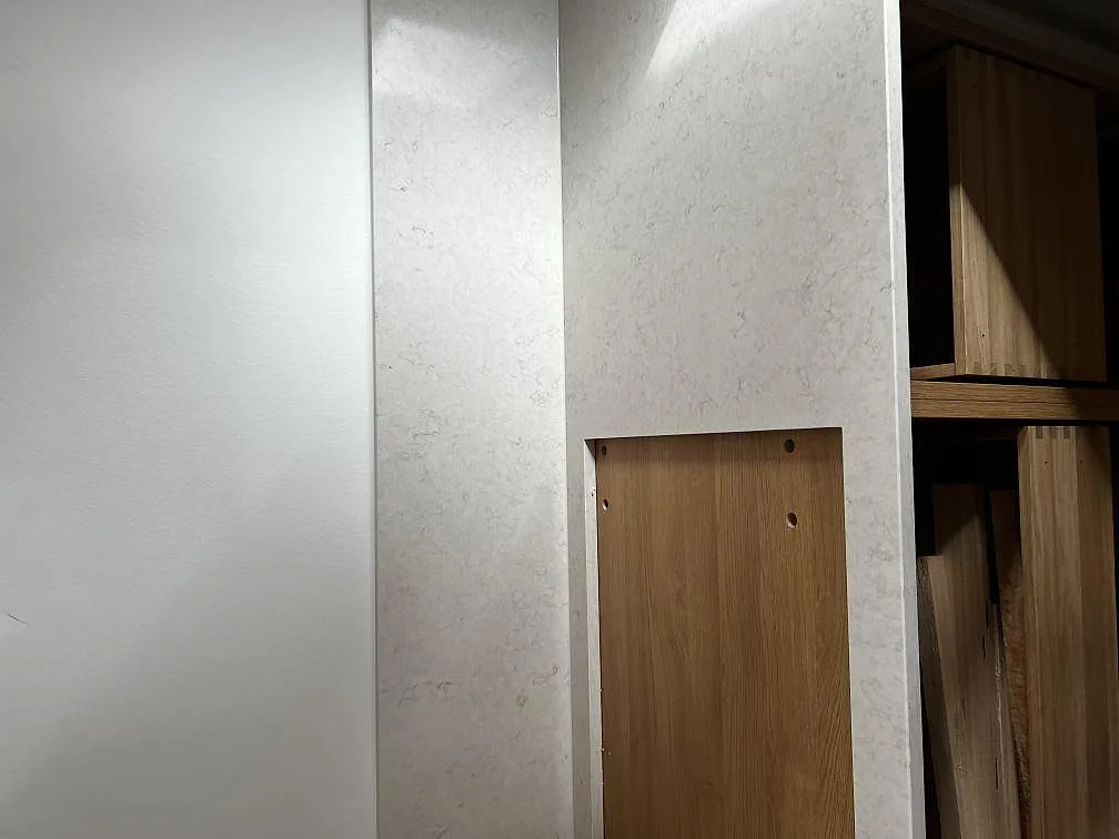 Vertikalt sidoparti i polerad Silestone Snowy Ibiza monterat vid träinredning i kök i Dyssegård.