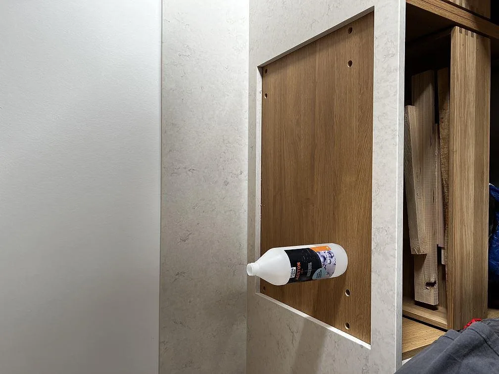 Detaljbild av polerad Silestone Snowy Ibiza runt sidopanel och träinredning under köksmontering i Dyssegård.