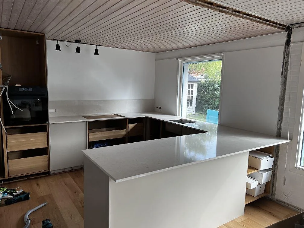 Köksbänkskiva i vit polerad Silestone Snowy Ibiza med halvö, hällurtag och övermonterad rostfri diskho i Dyssegård.