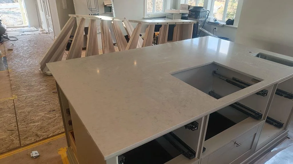 Köksö i vit kvartskomposit Silestone Snowy Ibiza med synlig ådring, hällöppning och stor fönsteryta i Ellös.