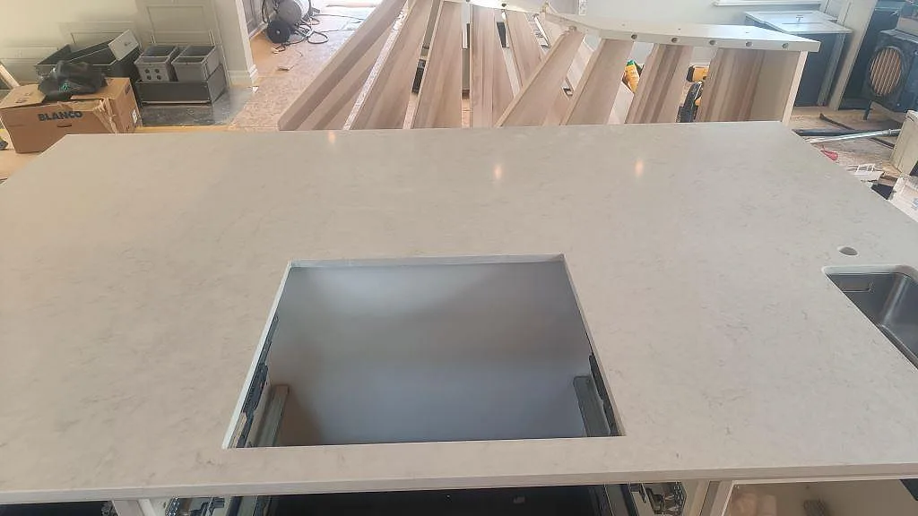 Närbild på polerad Silestone Snowy Ibiza med hällöppning, underlimmad rostfri diskho och installerad köksö i Ellös.