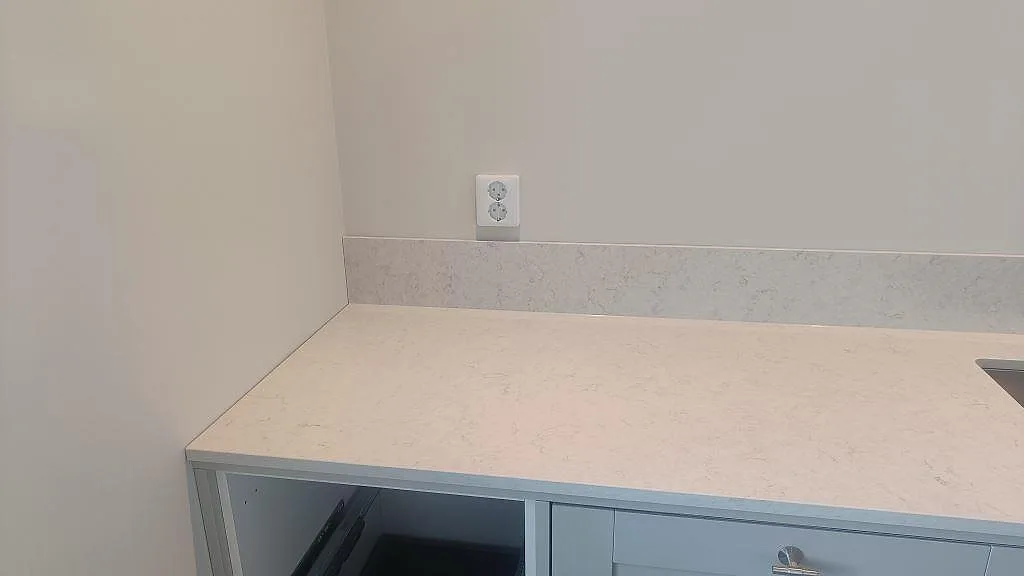 Låg stänkkant och bänkskiva i polerad Silestone Snowy Ibiza monterade mot vägg i kök i Ellös.