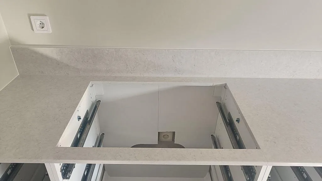Köksbänkskiva i ljus Silestone Snowy Ibiza med hälluttag och vita köksstommar under montering i Falkenberg.