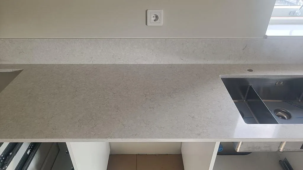 Köksbänkskiva i Silestone Snowy Ibiza med rostfri dubbelho, blandarhål och låg stänkkant i Falkenberg.
