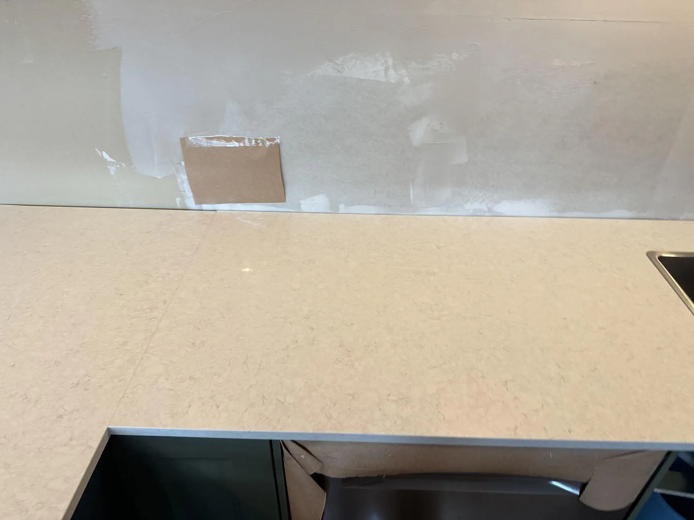 Lång bänkskiva i polerad Silestone Snowy Ibiza med ljus ådring framför ofärdig vägg i ett kök i Falkenberg.