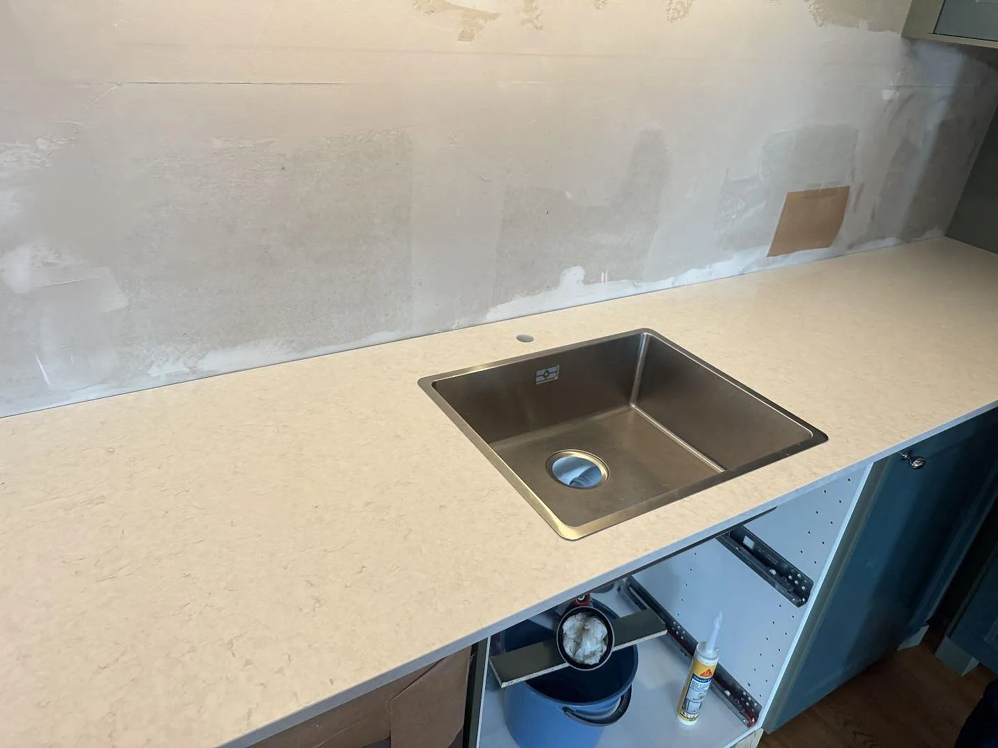 Köksbänkskiva i polerad Silestone Snowy Ibiza med rostfri diskho och blandarhål under montering i Falkenberg.