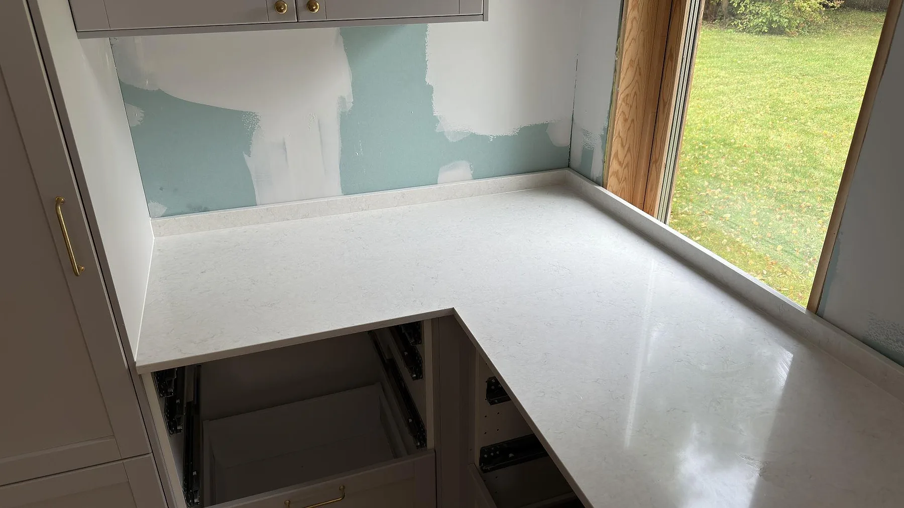 Närbild på polerad Silestone Snowy Ibiza som köksbänkskiva med L-format hörn, låg stänkkant och förberett urtag i Farsta.