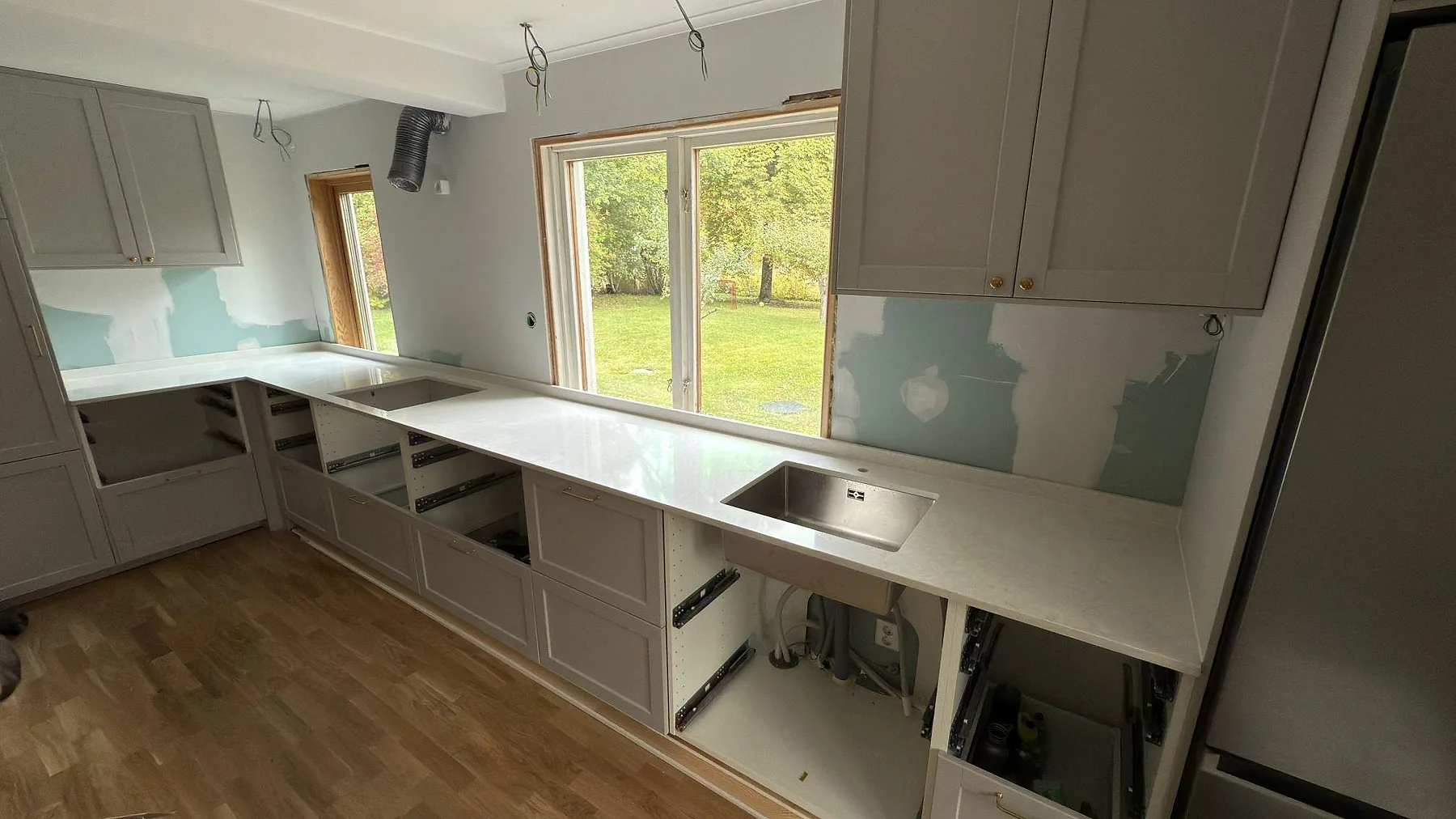 Köksbänkskiva i vit Silestone Snowy Ibiza, polerad komposit, monterad i L-form med rostfri diskho och låg stänkkant i Farsta.
